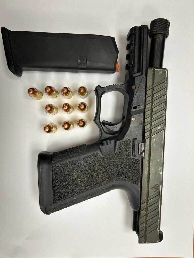 Pistola negra con balas y cargador encima papel.