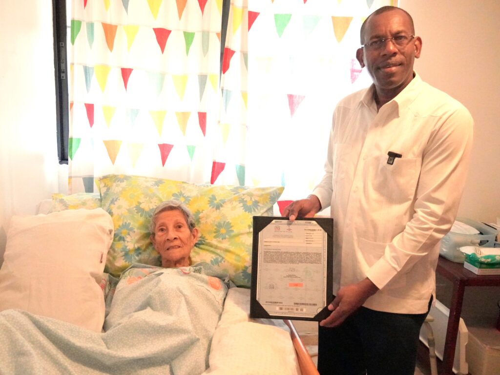 Hombre con diploma junto a mujer mayor en cama.