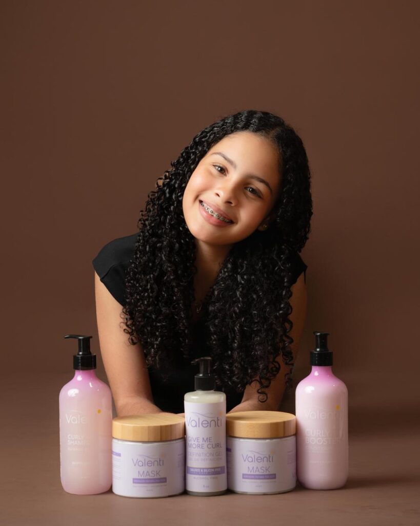 Niña sonriente con productos para cabello rizado Valenti.