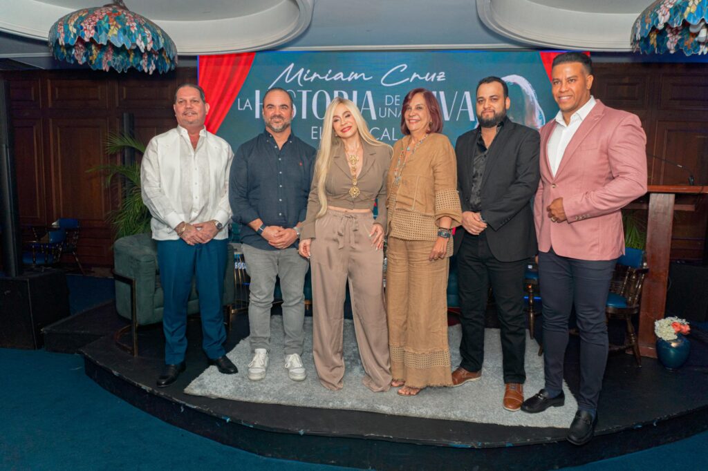 Grupo de personas en evento con cartel detrás.