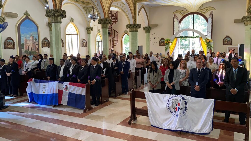 Ceremonia en iglesia con banderas y personas de pie.
