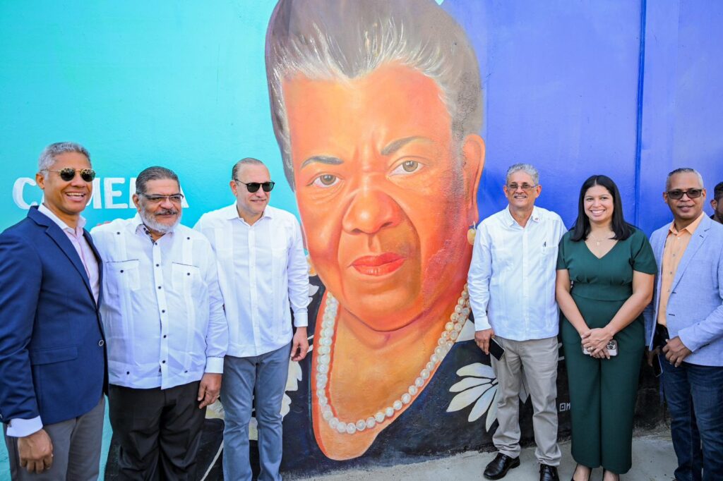 Grupo posando junto a mural colorido en una pared.