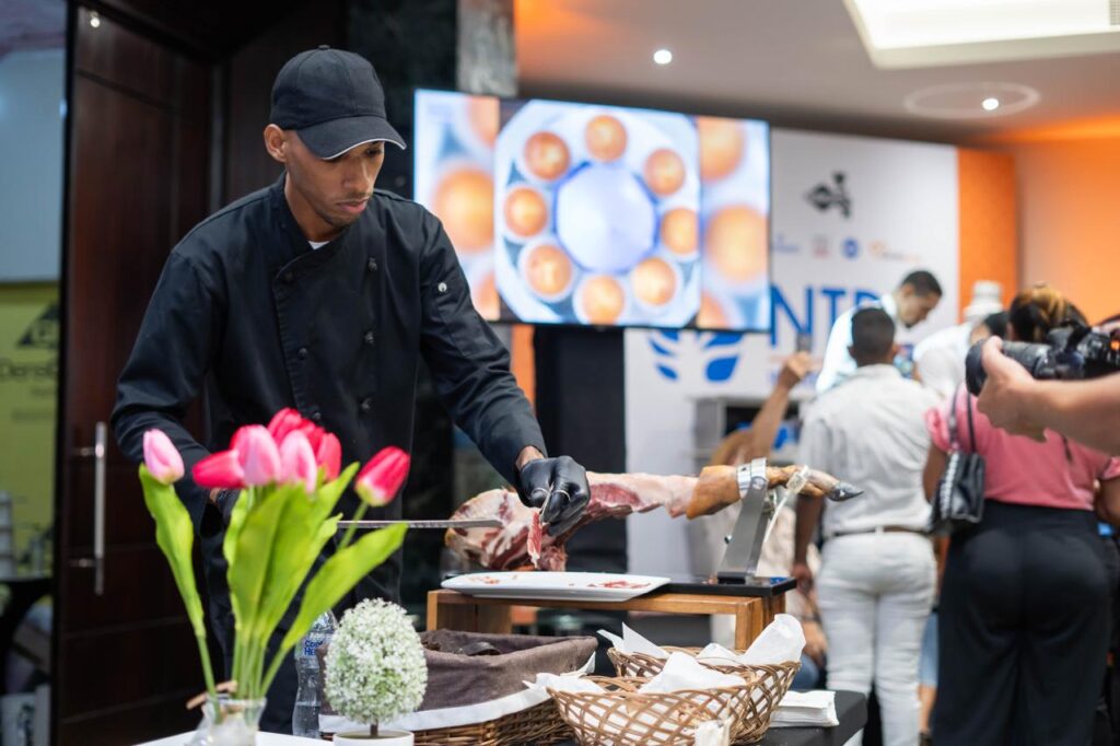 Chef cortando jamón en evento gastronómico.