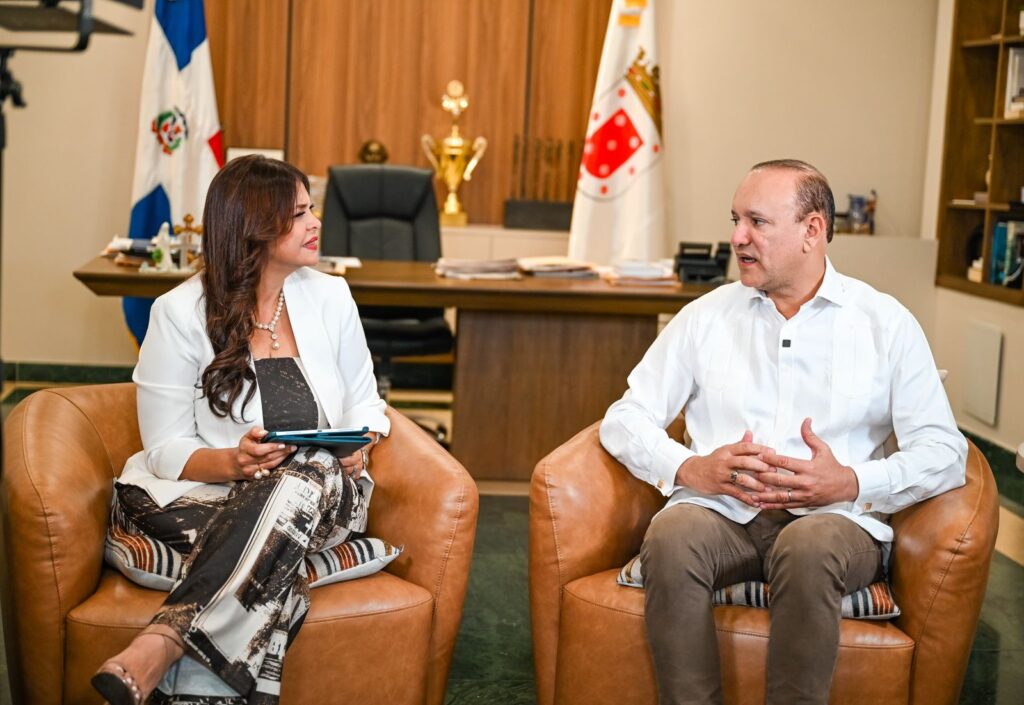 Entrevista en oficina con banderas y trofeos.