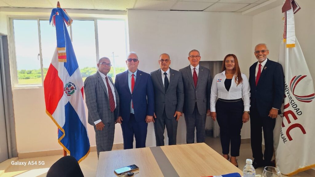 Grupo de personas junto a banderas en oficina.