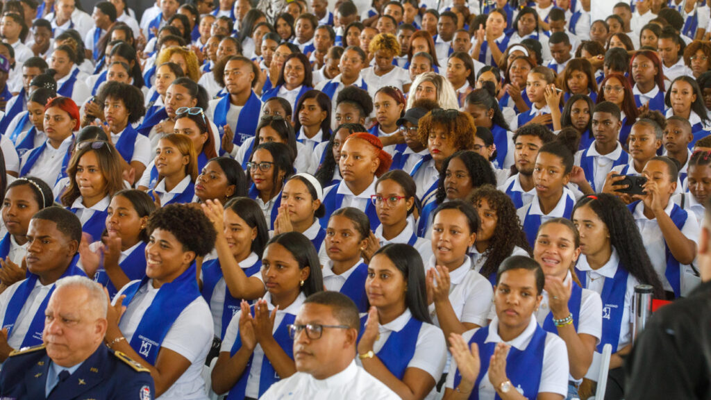 Estudiantes en ceremonia con uniformes formales y escudos azules.