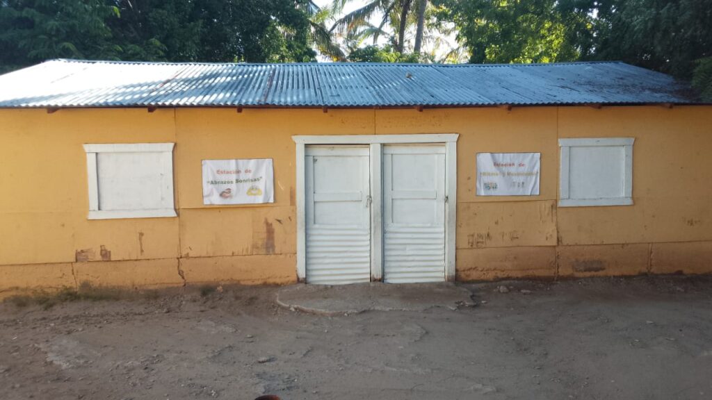 Edificio amarillo con carteles y puerta blanca.