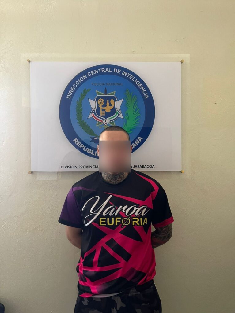 Hombre frente a cartel de policía dominicana.