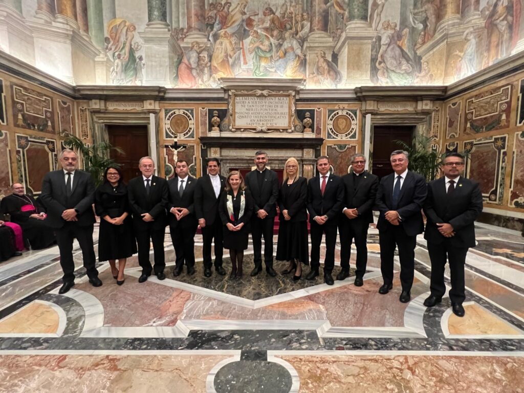Grupo de personas en un salón histórico decorado.