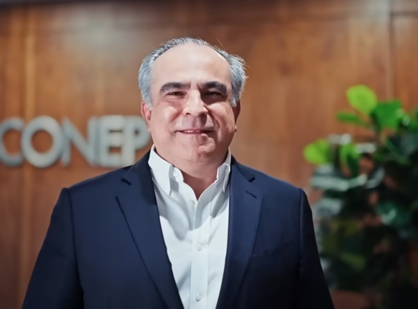 Hombre sonriendo frente a planta y logo CONEP