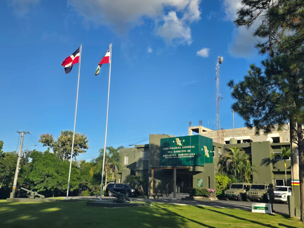 Edificio militar con banderas y cielo azul.
