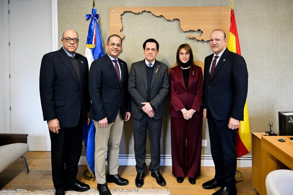 Grupo de personas frente a banderas y mapa.