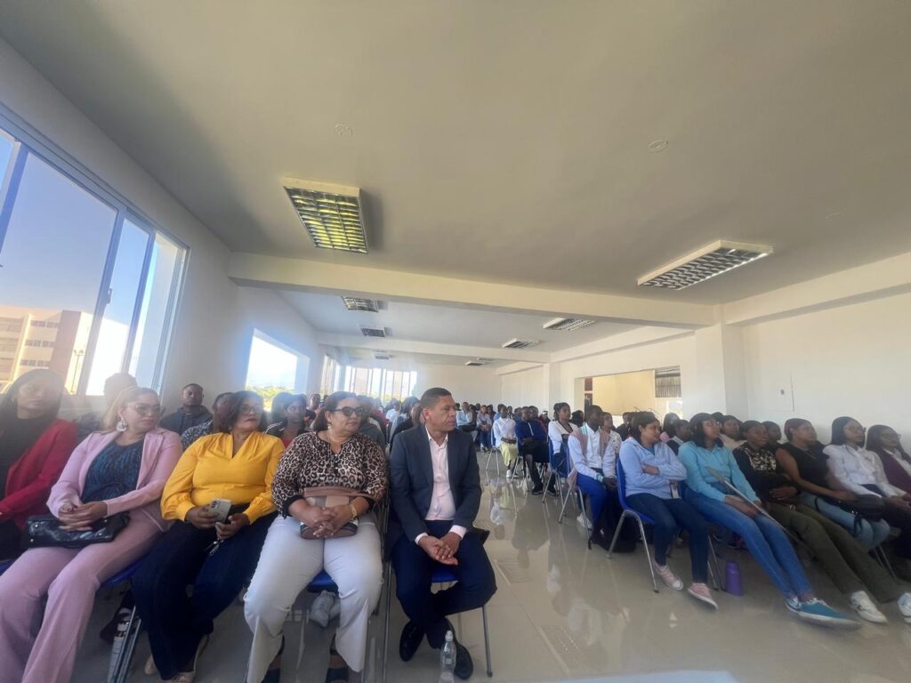 Personas asistiendo a conferencia en sala iluminada.