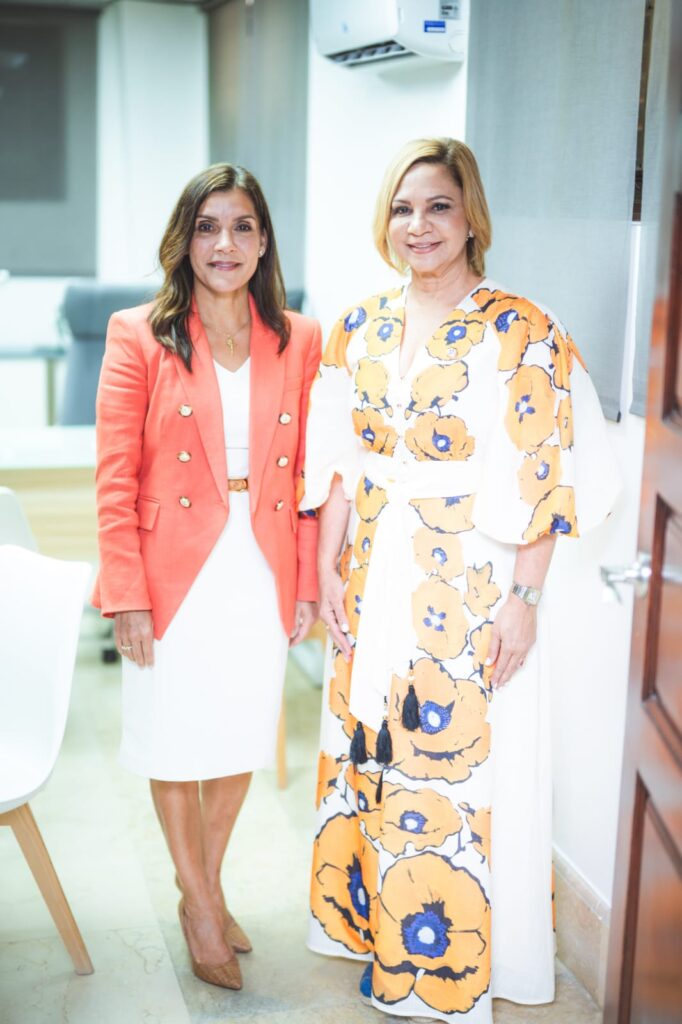 Dos mujeres posando en oficina moderna.