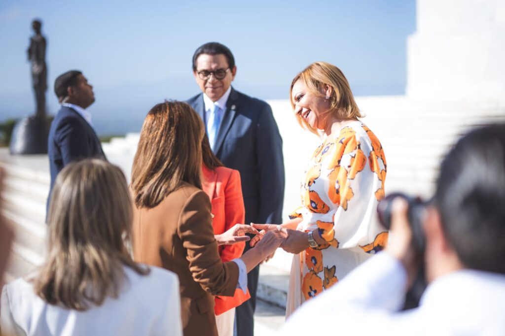 Personas saludando en evento formal al aire libre.