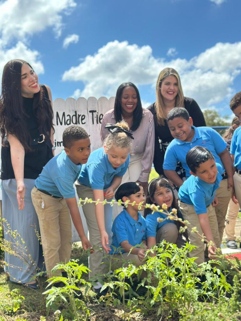 Niños y maestras plantando en el jardín escolar