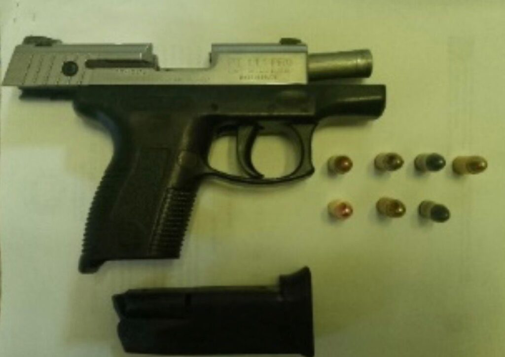 Pistola con cartuchos sobre papel blanco