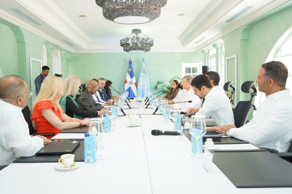 Personas en reunión oficial con banderas dominicanas.