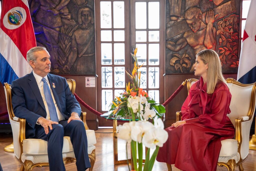 Reunión diplomática en sala con banderas y flores