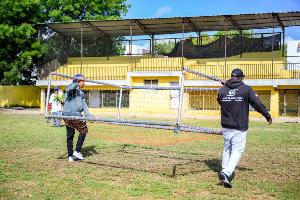 Personas moviendo portería de fútbol en un campo