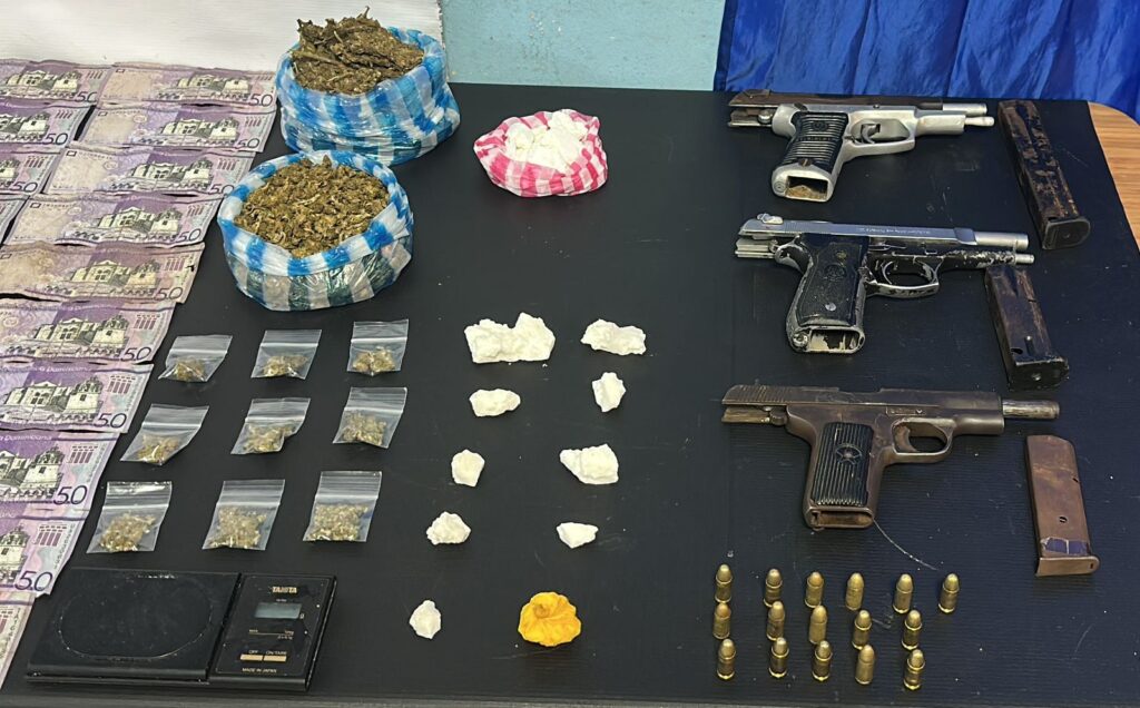 Drogas, dinero y armas en una mesa negra.
