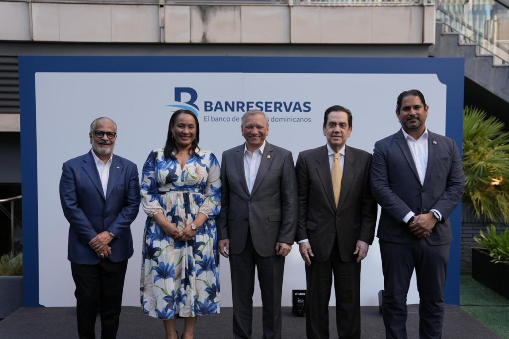 Cinco personas posan frente a cartel de Banreservas.