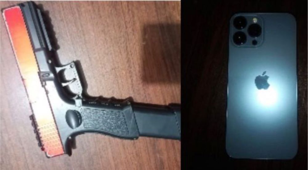 Pistola de juguete y teléfono móvil en mesa.