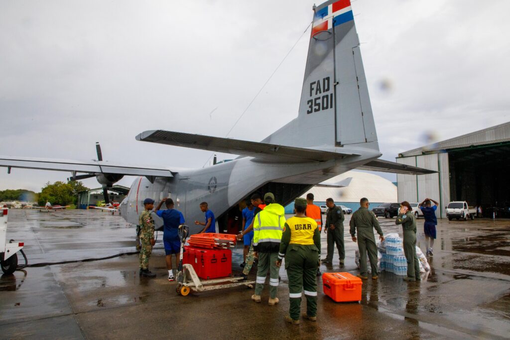 Soldados descargan suministros de avión militar en aeropuerto.