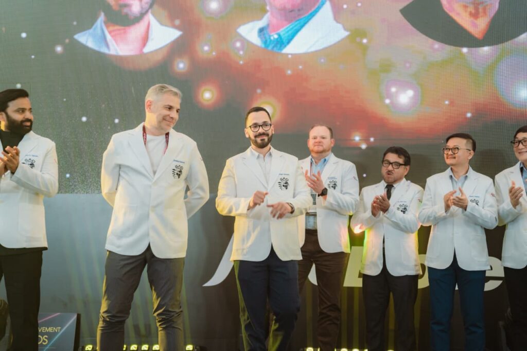 Hombres en chaquetas blancas aplaudiendo en un evento.