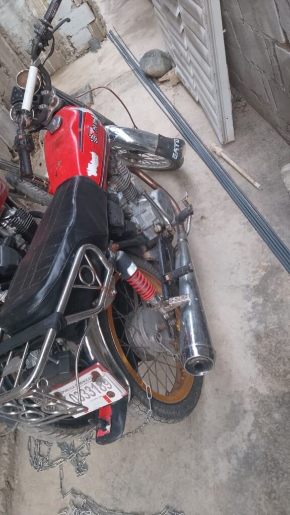Motocicleta roja aparcada en garaje con cadenas.