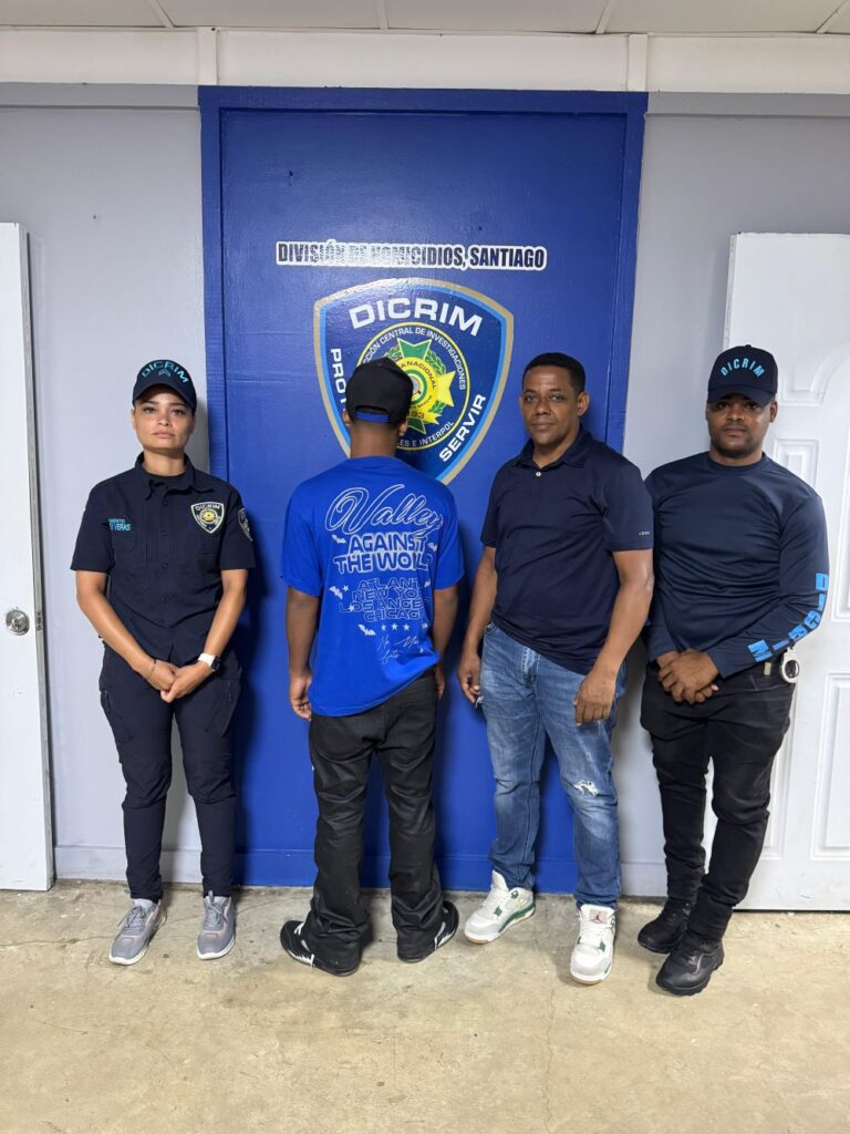 Personas posando frente a puerta de oficina policial.