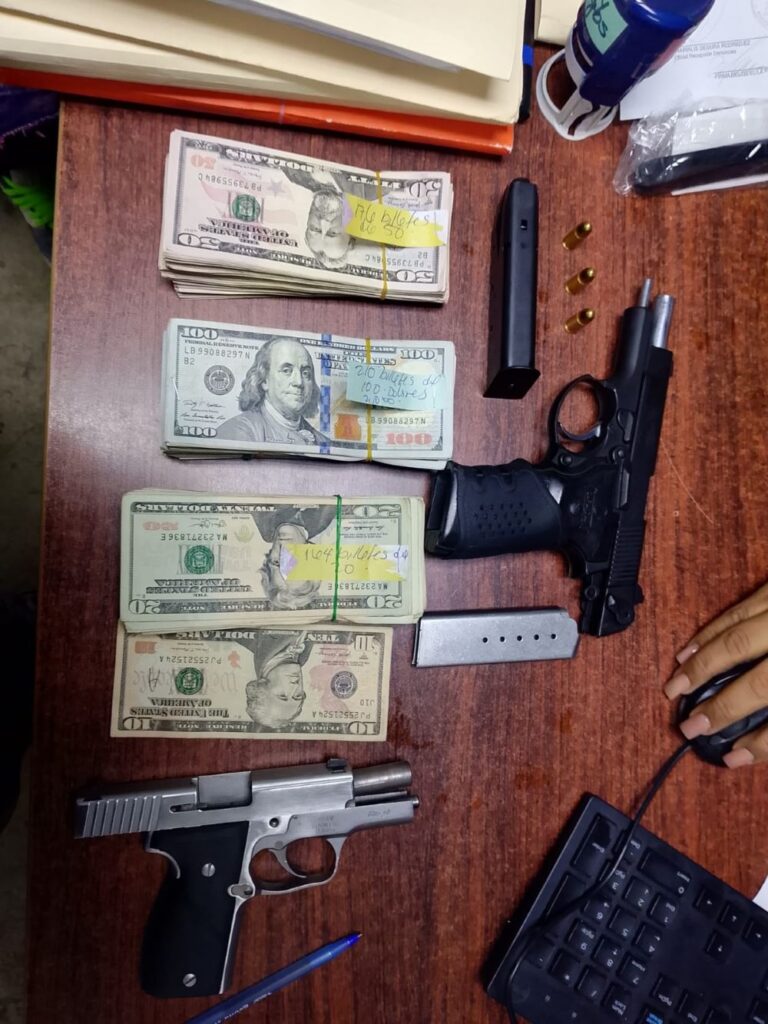 Dinero en efectivo y pistolas sobre mesa de oficina.