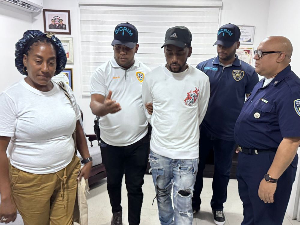 Arresto policial en oficina con varias personas presentes.