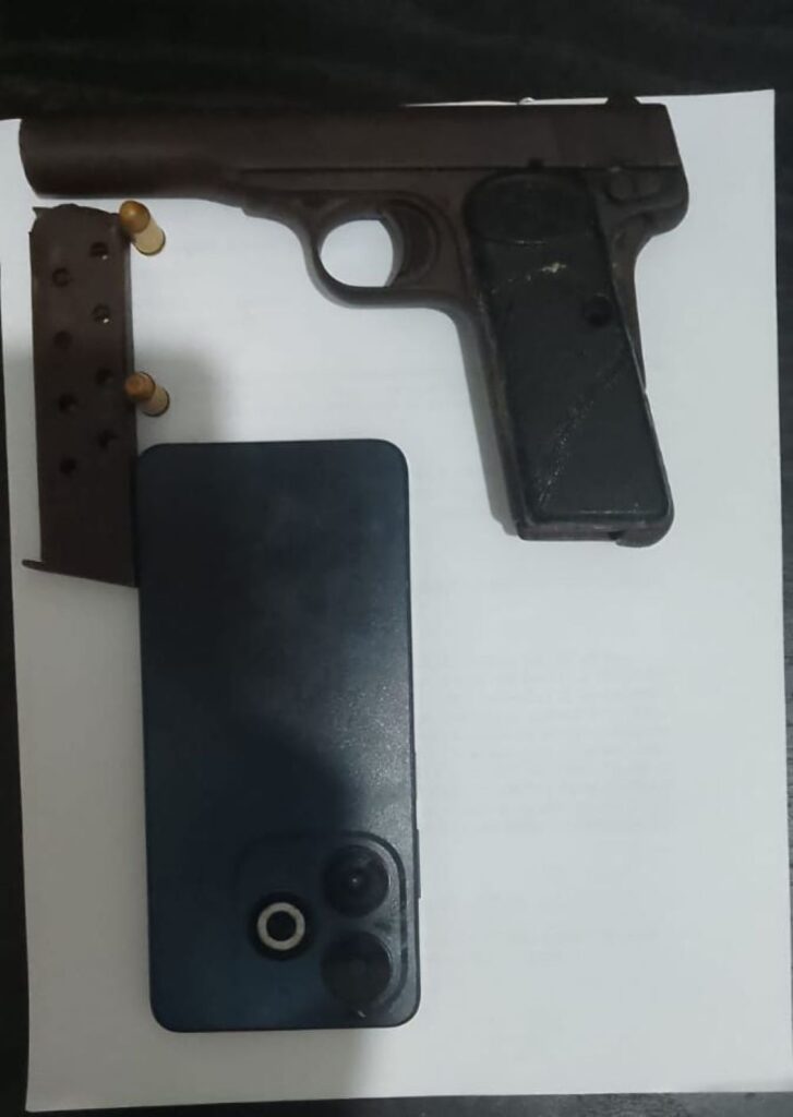 Pistola, cargador y móvil sobre papel blanco.