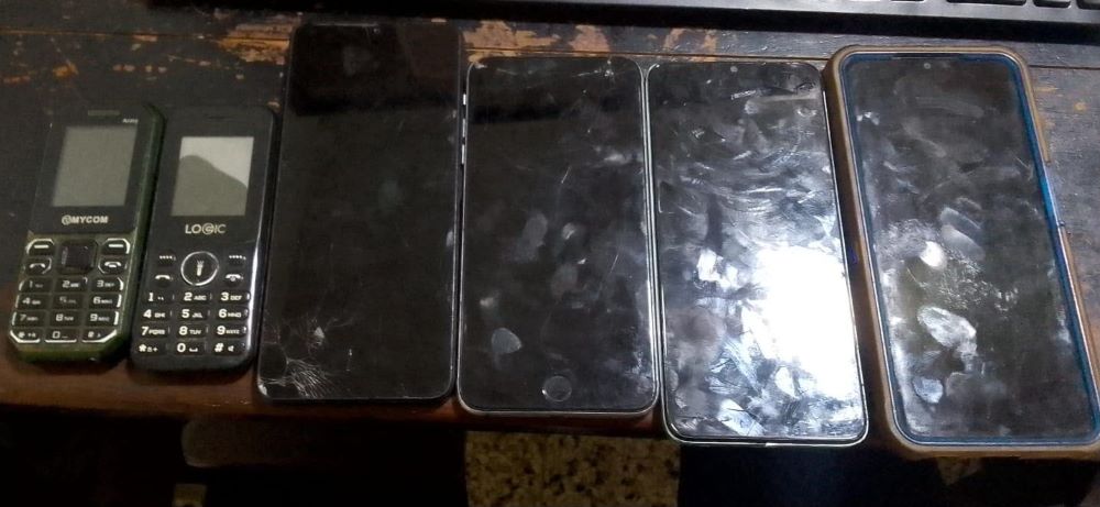 Cinco móviles en fila sobre una mesa antigua.