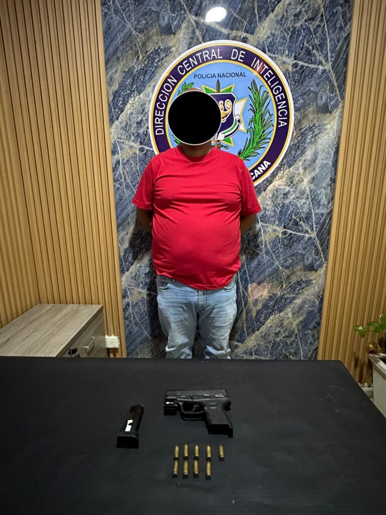 Persona detenida con pistola y balas en mesa.