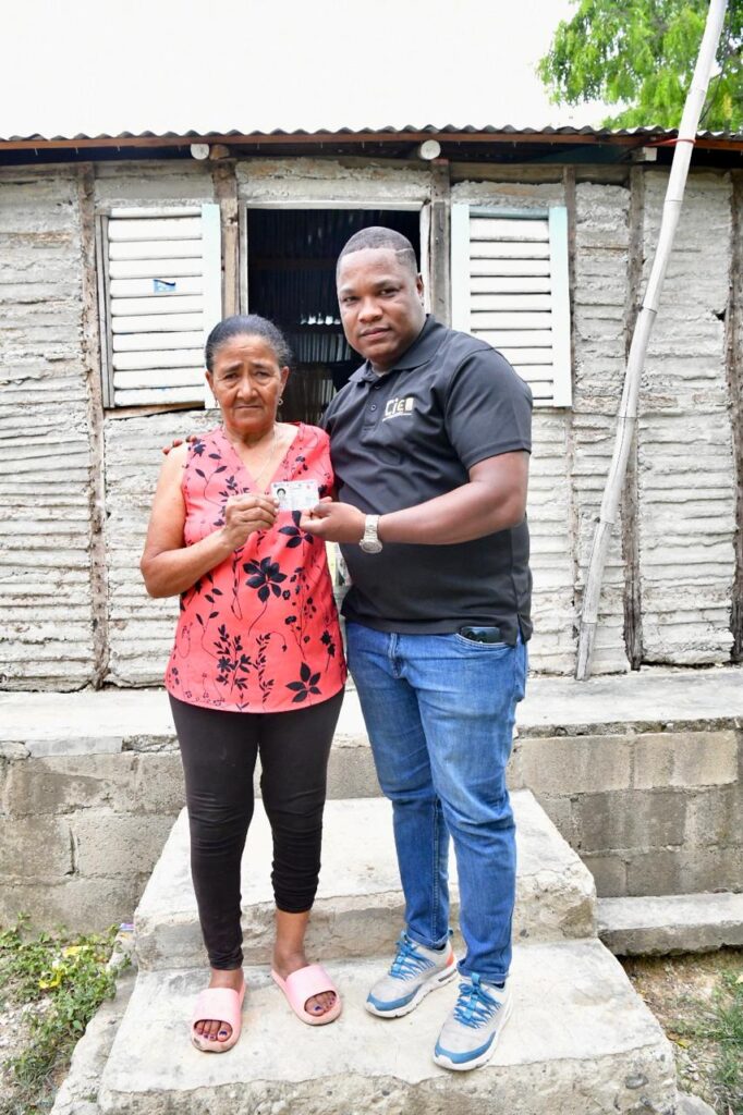 Pareja mostrando documento frente a casa de madera.