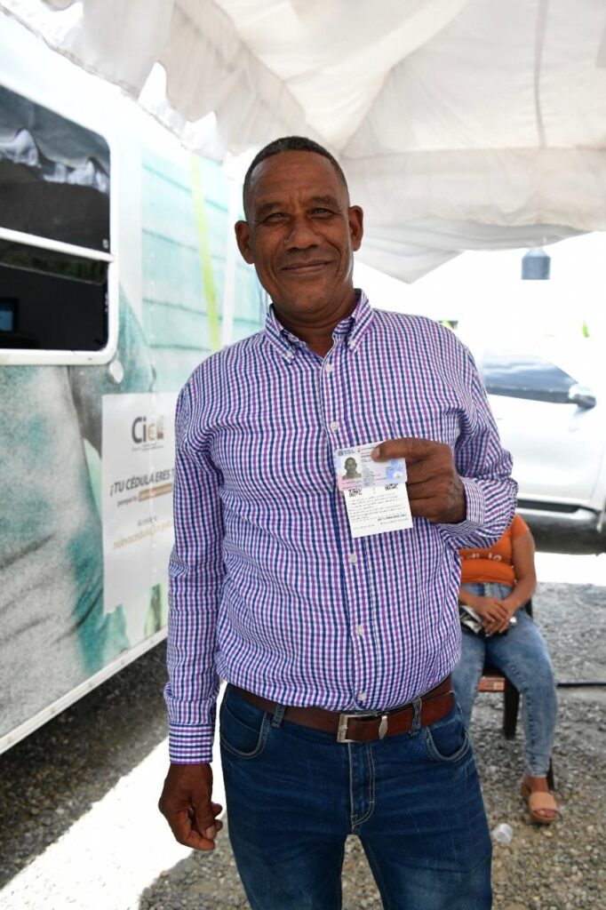 Hombre sonriente mostrando documento de identidad.