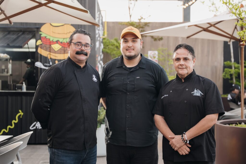 Tres chefs posando en un restaurante al aire libre.