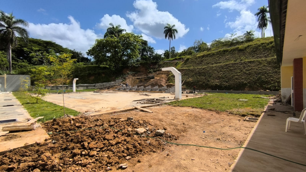 Obra en construcción con paisaje y palmeras.